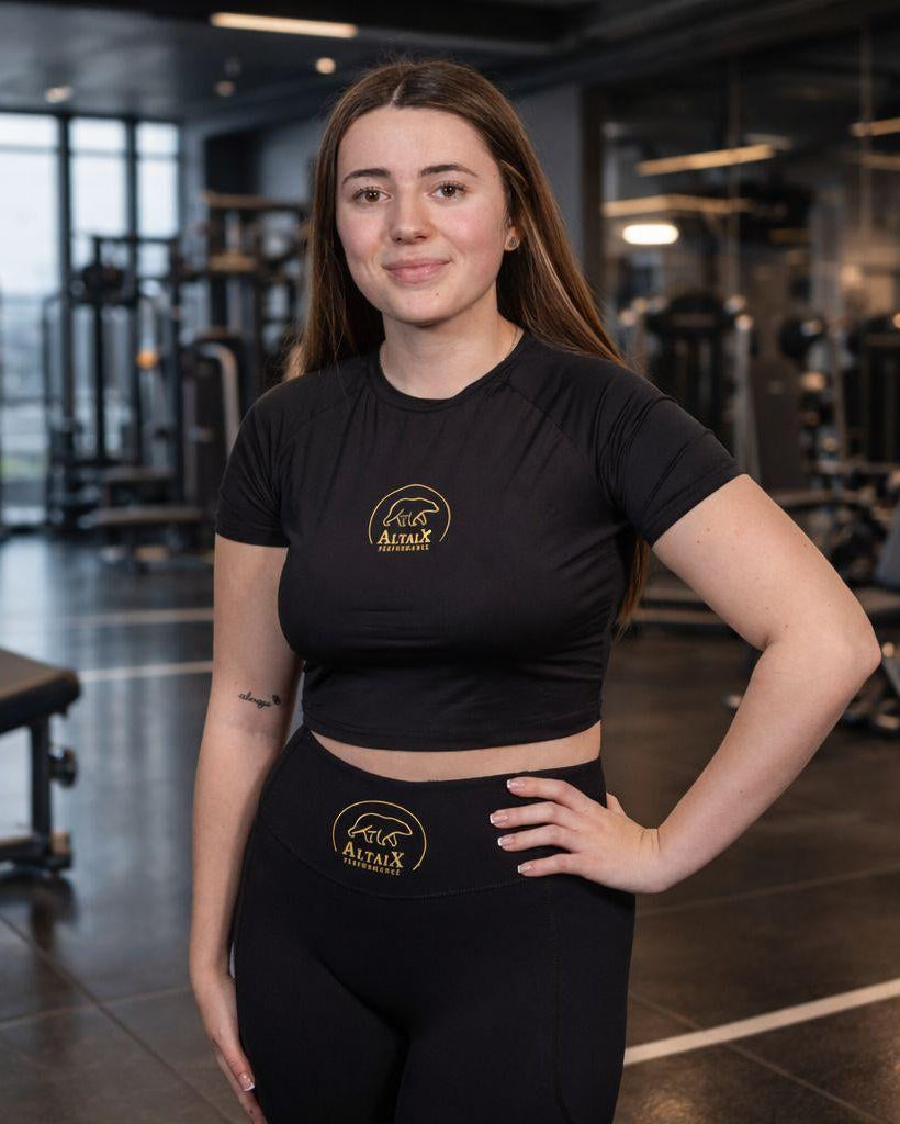 Woman in black athletic wear with a brand logo in a gym setting